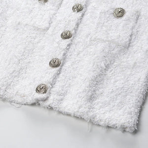 Close-up of a white textured fabric with metallic buttons on a light gray background
