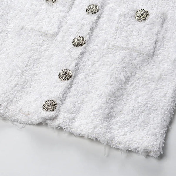 Close-up of a white textured fabric with metallic buttons on a light gray background