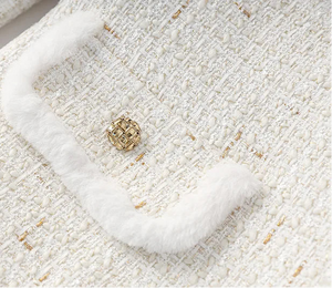 Close-up of a textured white fabric with a gold button.
