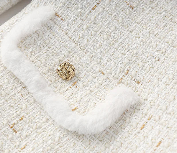 Close-up of a textured white fabric with a gold button.