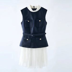 Navy vest with white collar and pleated skirt on a hanger against a light gray background