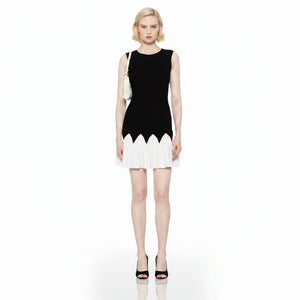 Black dress with white pleated hem worn by a model on a white background