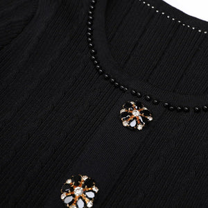 Black beaded necklace with floral pendants on a black background