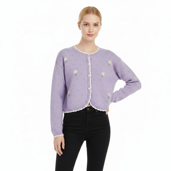 Woman wearing a light purple cardigan with floral embellishments on a white background