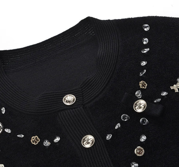 Black sweater with decorative buttons and embellishments on a white background