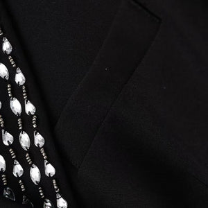 Close-up of a black blazer with a patterned fabric on a black background