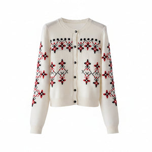 White sweater with red and black patterns on a wooden hanger against a white background