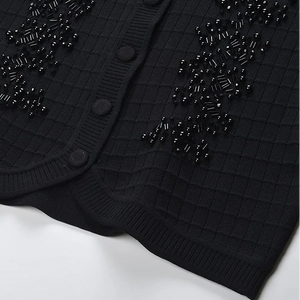 Black cardigan with bead embellishments on a white background