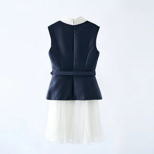 Navy blue sleeveless top with a white pleated skirt on a hanger against a light gray background