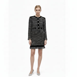 Woman wearing a black and white tweed dress with a matching handbag on a white background