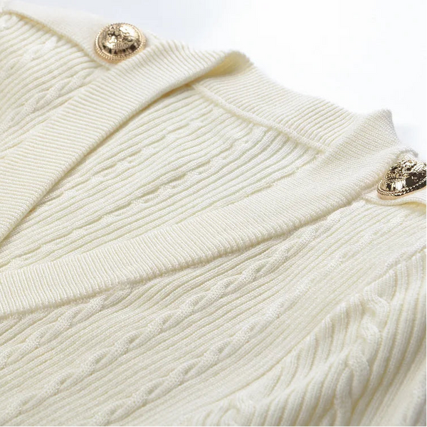 Close-up of a cream-colored textured fabric with gold buttons on a white background
