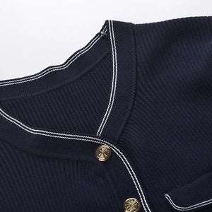 Close-up of a navy blue garment with white piping and gold buttons on a light gray background