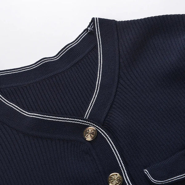 Close-up of a navy blue garment with white piping and gold buttons on a light gray background
