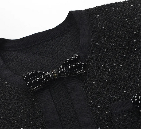 Black sequined garment with a bow detail on a white background