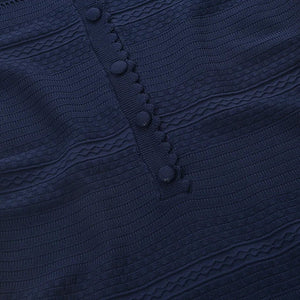 Close-up of a navy blue textured garment with buttons on a white background