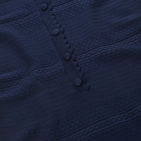 Close-up of a navy blue textured garment with buttons on a white background