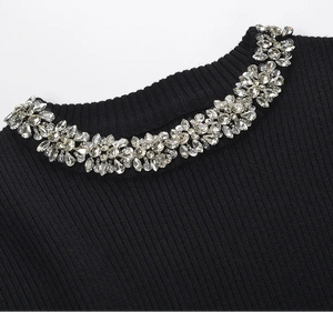 Black sweater with a decorative silver necklace on a white background