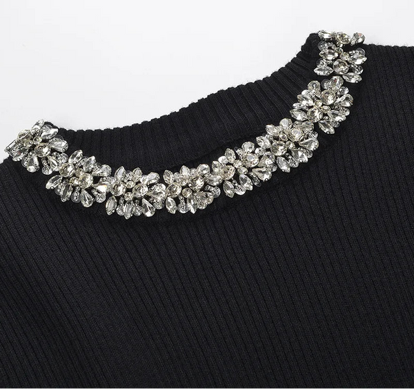 Black sweater with a decorative silver necklace on a white background