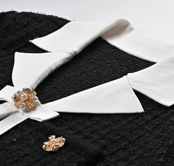 White collar with gold earrings on a black textured surface
