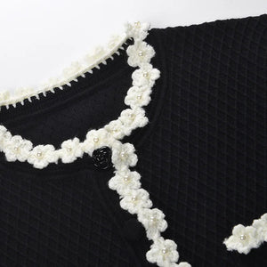 Black garment with white floral lace trim on a white background