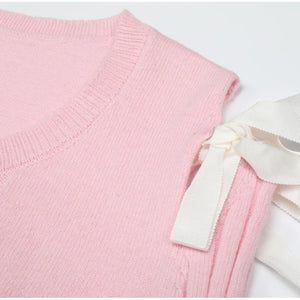 Pink sweater with a white bow on a light gray background