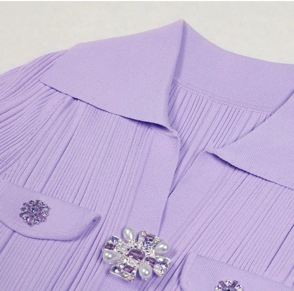 Close-up of a purple garment with a brooch on a light gray background