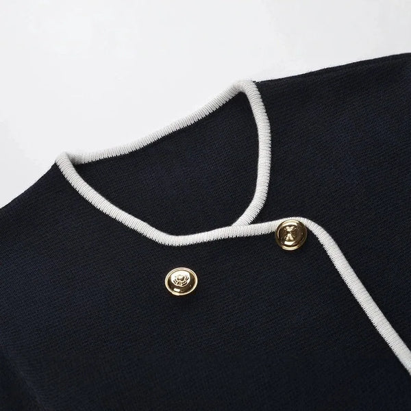 Close-up of a black garment with white trim and gold buttons on a white background