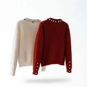 Two sweaters, one beige and one red, on hangers against a white background.