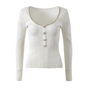 White ribbed long-sleeve top with decorative buttons on a white background