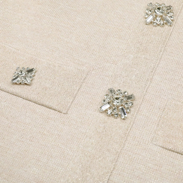 Close-up of a beige fabric with crystal buttons on a matching beige background