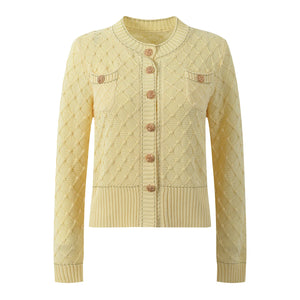 Light yellow cable knit cardigan with button details on a white background