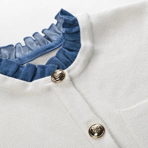 White garment with blue ruffled collar and gold buttons