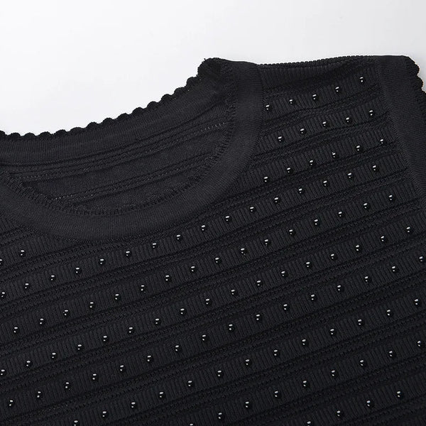 Black textured sweater with stud details on a white background