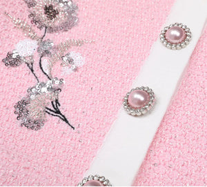 Pink fabric with floral embellishments and a white ribbon