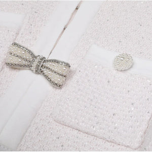 Close-up of a textured white fabric with a decorative bow and button.