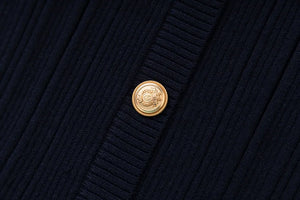 Close-up of a navy blue textured fabric with a gold button featuring a logo.