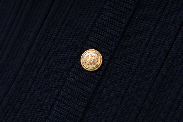 Close-up of a navy blue textured fabric with a gold button featuring a logo.