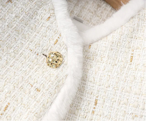 Close-up of a textured white fabric with a gold button