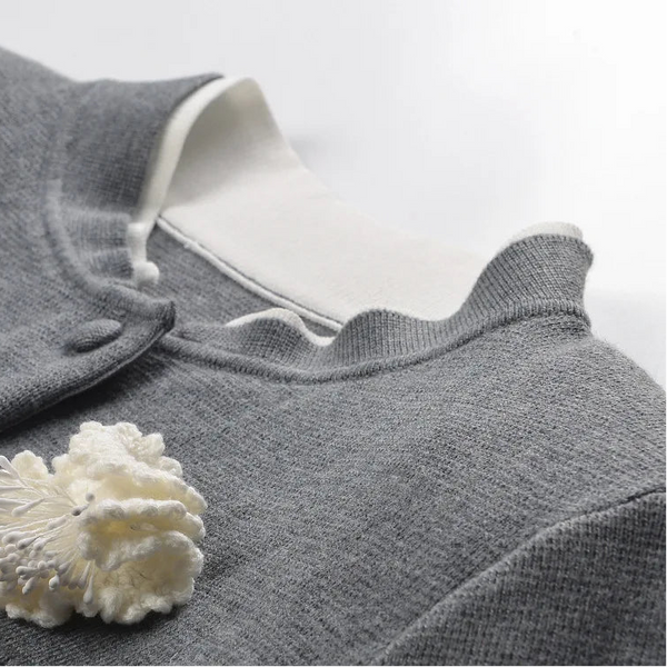 Gray garment with white floral accessory on a light gray background