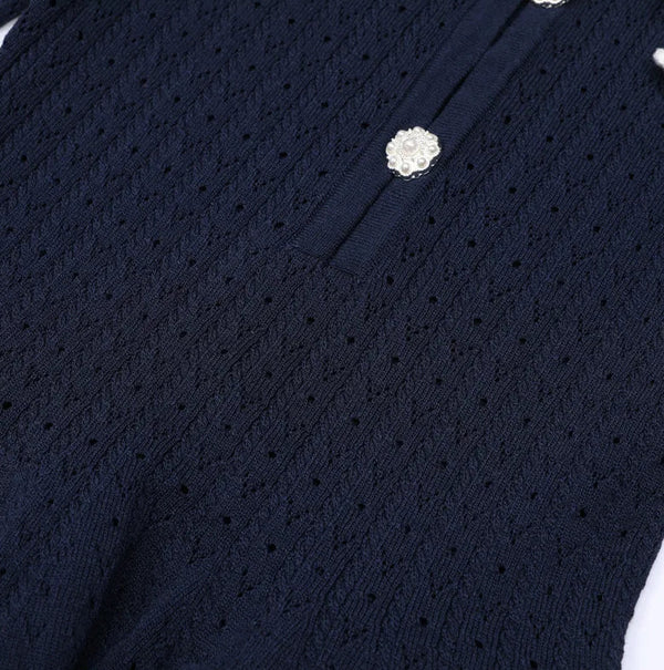 Navy blue cardigan with white floral embellishments on a white background