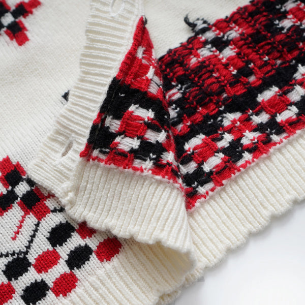 Close-up of a white sweater with red and black patterned sleeves on a white background