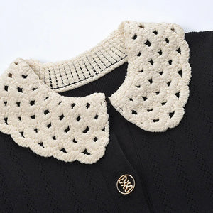 Black garment with a white crochet collar on a white background