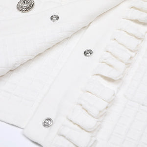 Close-up of a white textured fabric with buttons on a light background