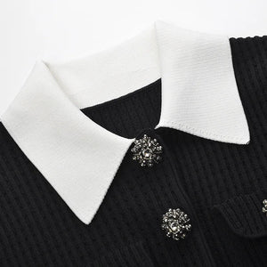 Black sweater with white collar and decorative buttons on a white background