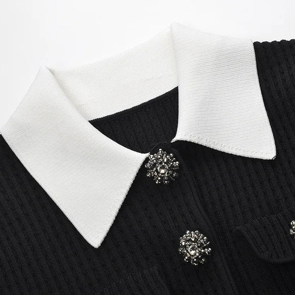 Black sweater with white collar and decorative buttons on a white background