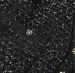Close-up of a black glittery handbag with a gold clasp.