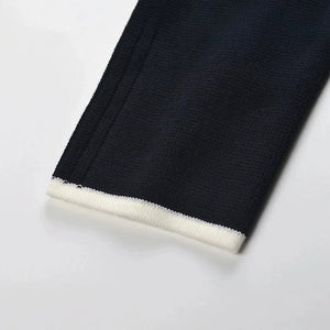 Close-up of black fabric with white trim on a light gray background