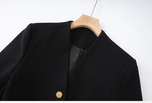 Black coat with a gold button on a wooden hanger against a white background