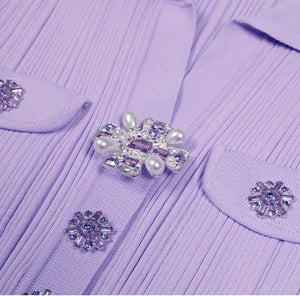 Close-up of a purple garment with decorative buttons featuring pearls and crystals.