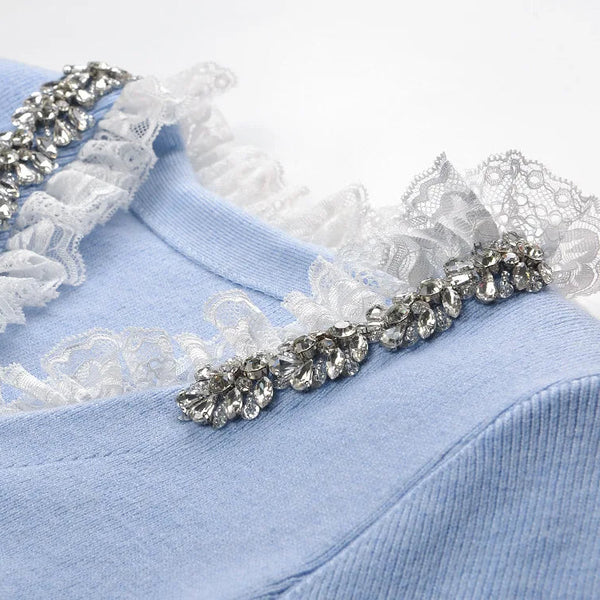 Close-up of a light blue garment with lace and embellishments on a white background